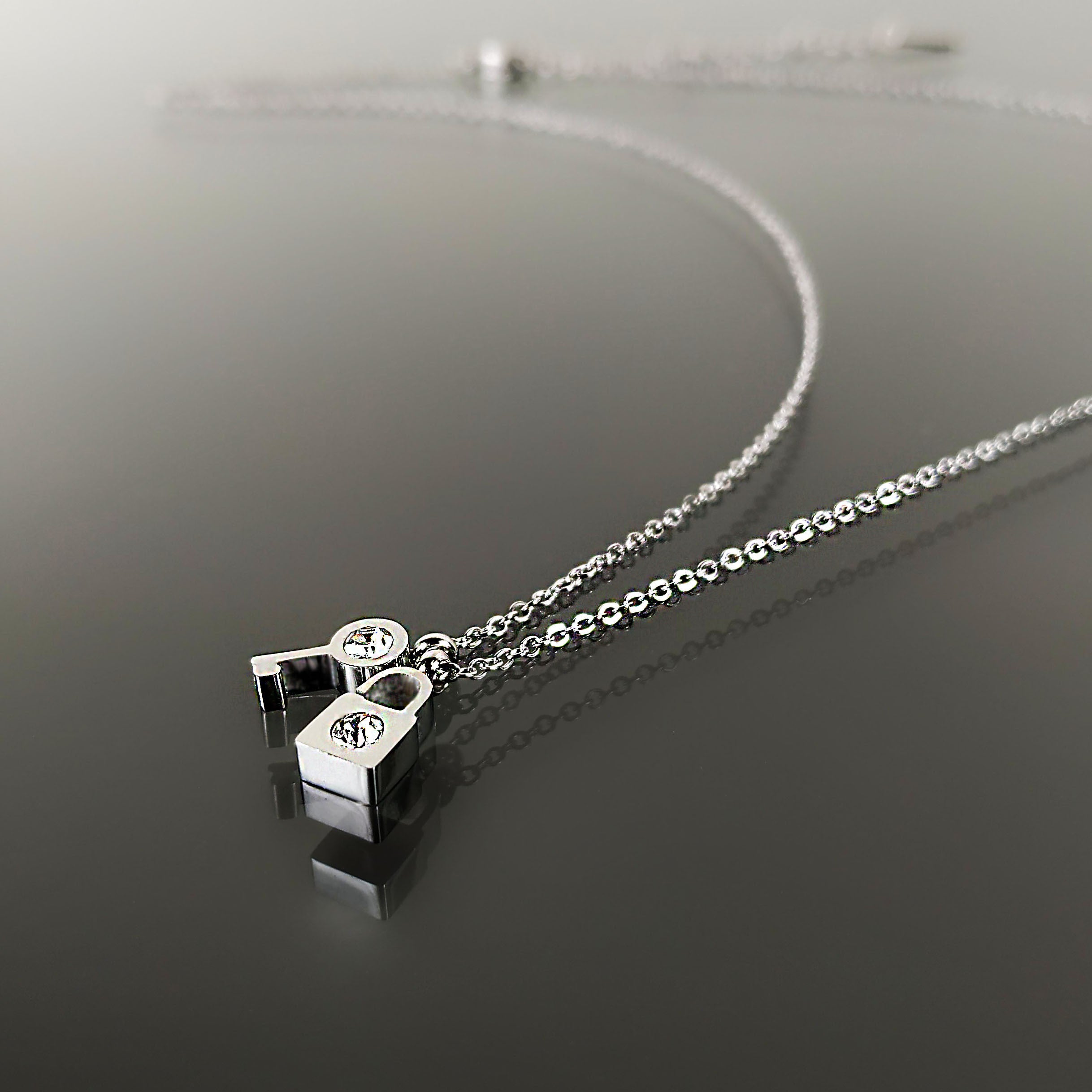 Krásný ocelový náhrdelník ve tvaru klíčku a zámku s čirými krystaly NK0641-0107
