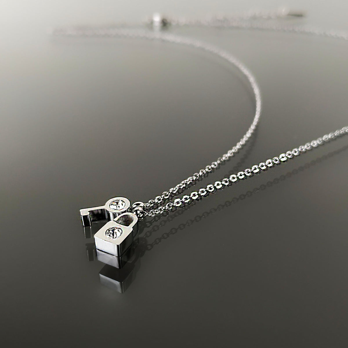 Krásný ocelový náhrdelník ve tvaru klíčku a zámku s čirými krystaly NK0641-0107